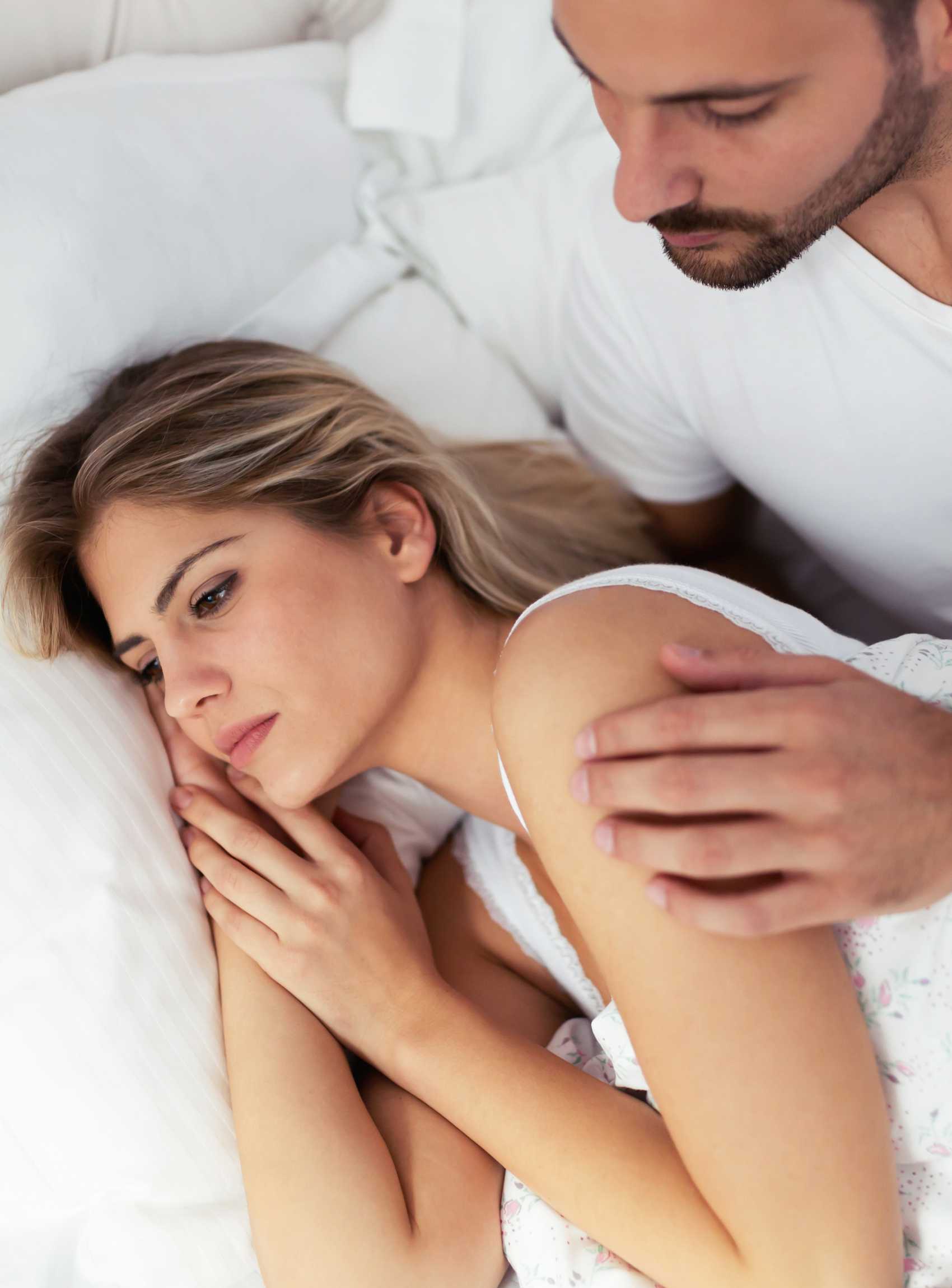 Un couple dans un lit, une femme tourne le dos à son mari