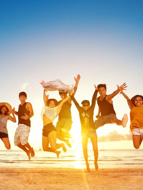 s'épanouir dans un groupe personnes qui sautent de joie ensemble sur une plage avec le coucher de soleil en fond