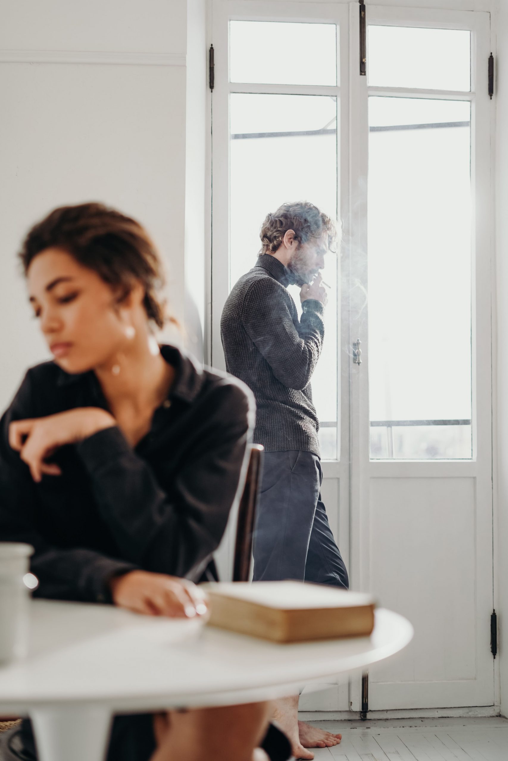 Un homme fume à la fenêtre et une femme fait la tête