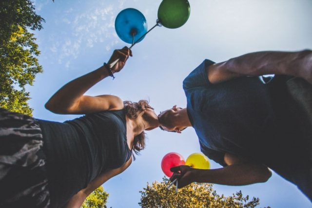 Couple vu d'en-bas qui s'embrasse et tient des ballons